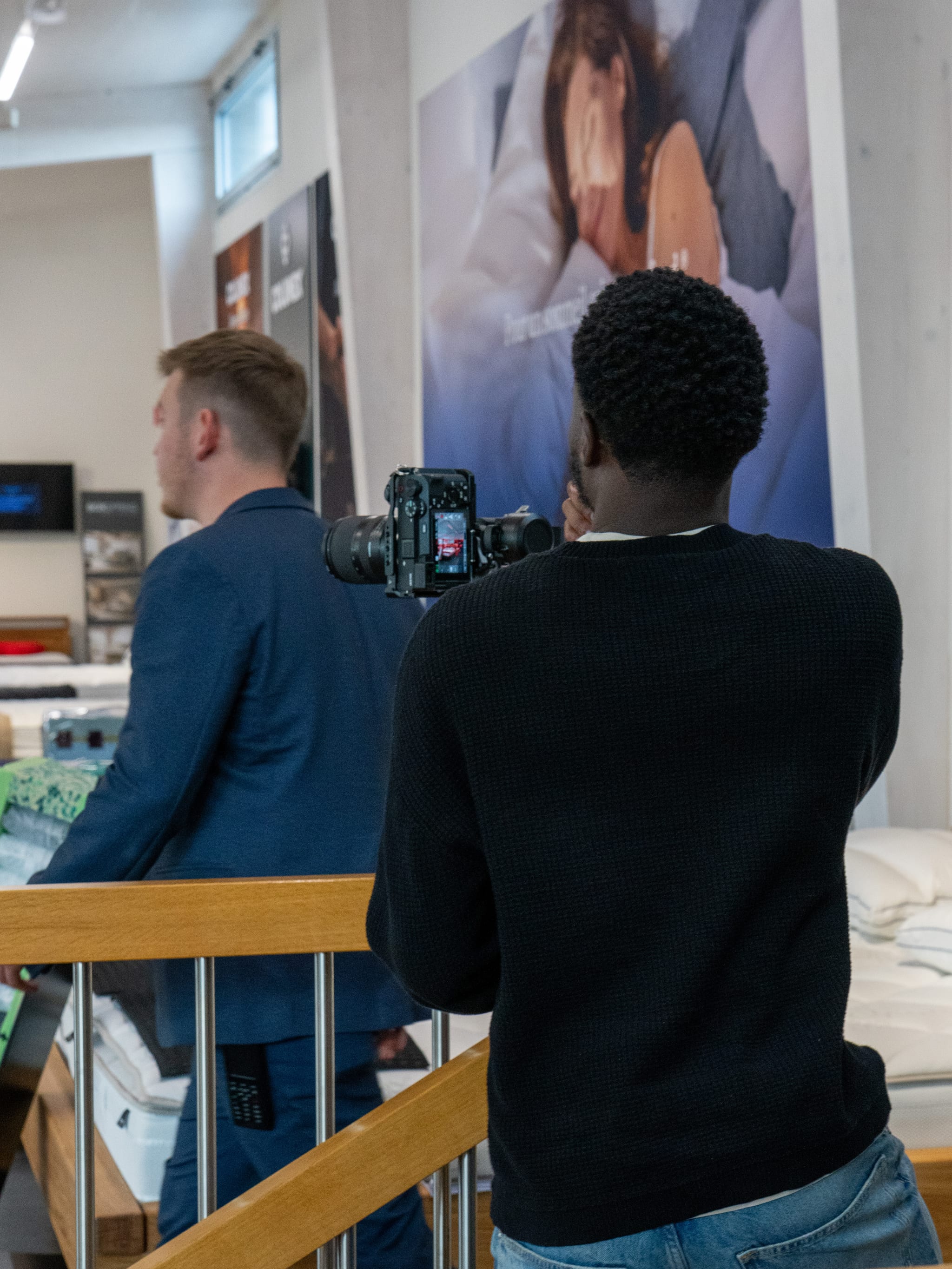 Tournage de la vidéo de présentation de Confort-lit : un vidéaste filme un homme en costume dans le magasin