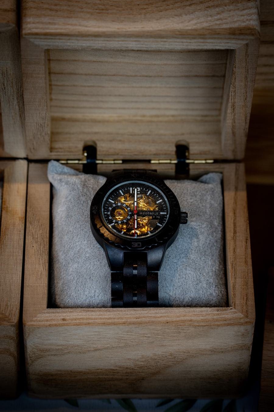 Montre Woodbold à cadran squelette posée sur un coussin, dans un coffret en bois ouvert