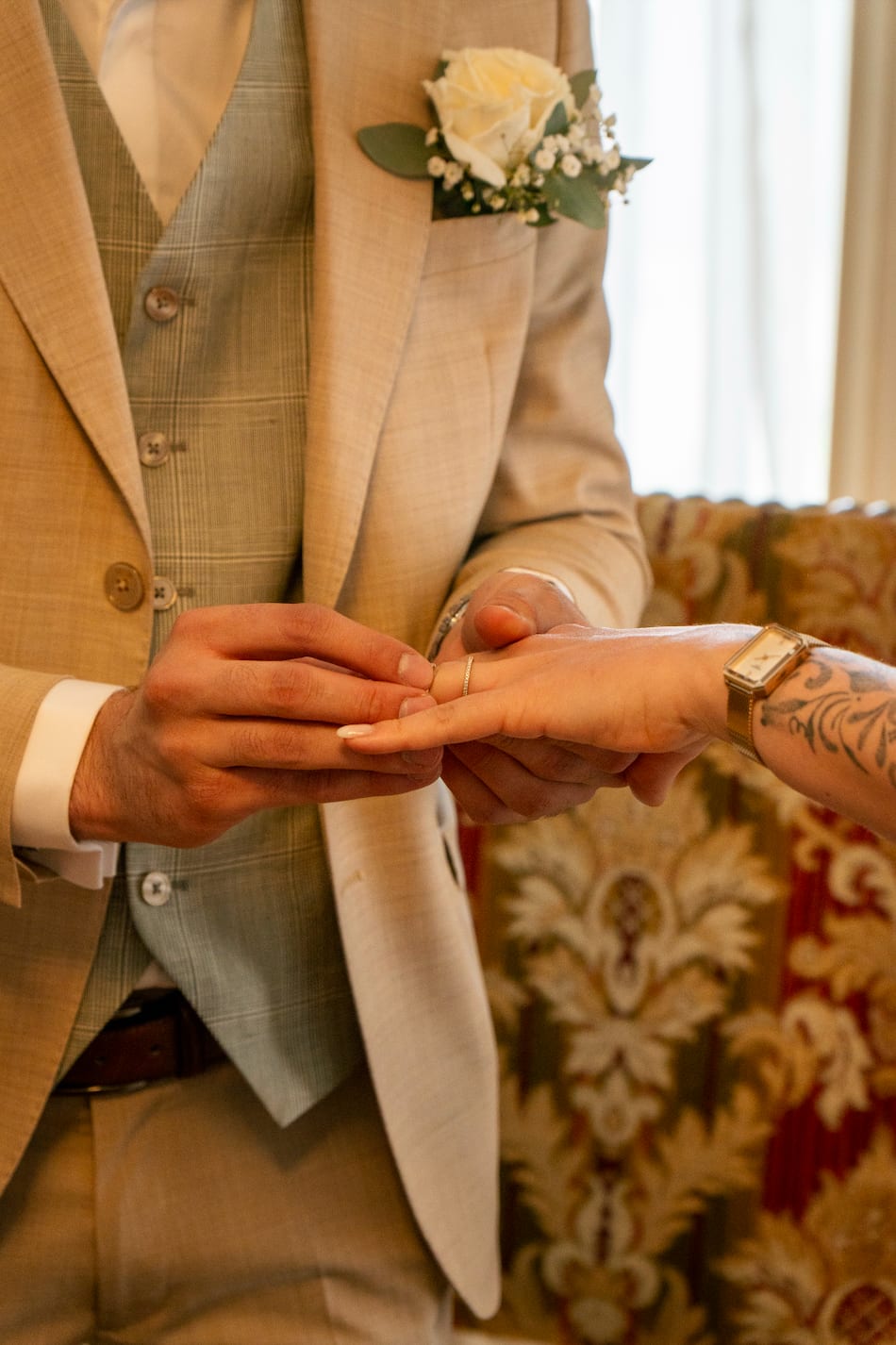 Steven passe l'alliance au doigt de Kenza, boutonnière de roses blanches au revers