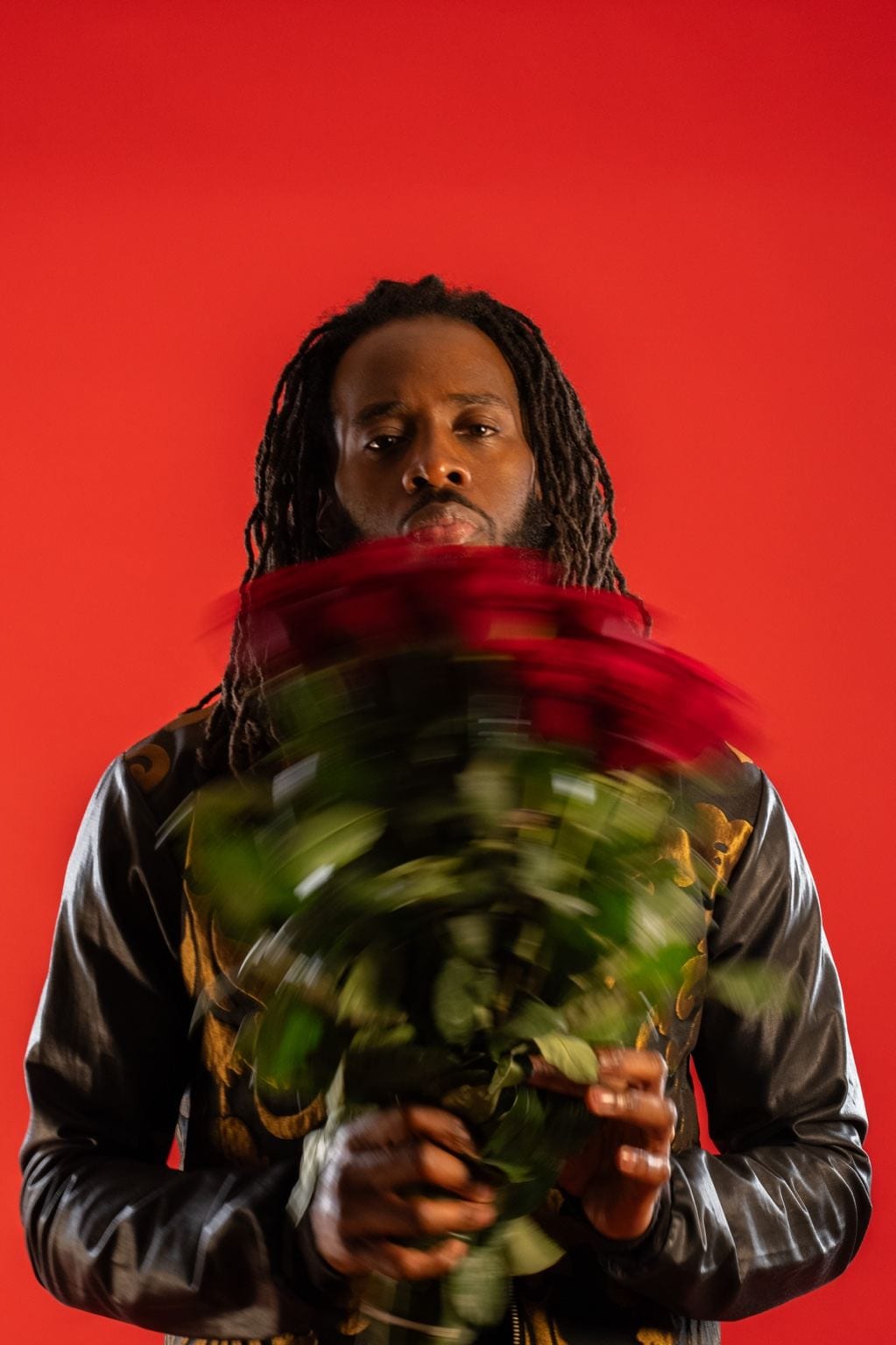 Jules tenant un bouquet de roses rouges devant un fond rouge